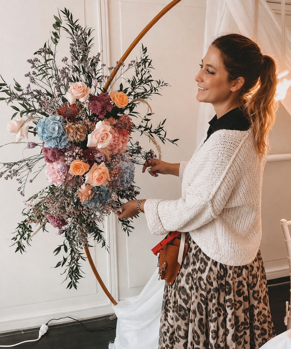 Floristin gestaltet ein großes Arrangement mit Rosen und Hortensien